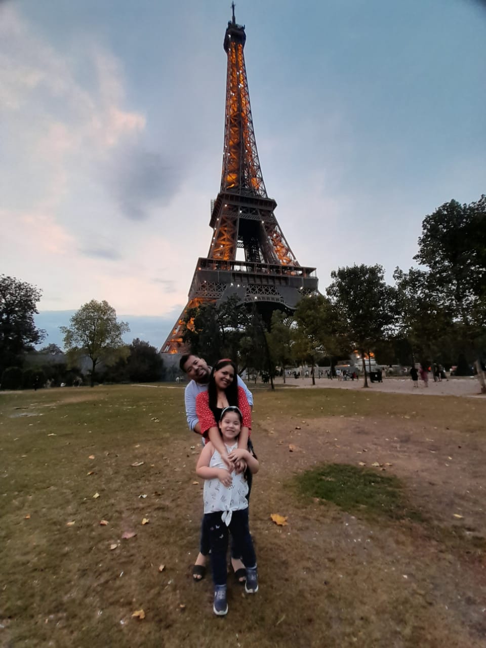 Image of a family (male, female, young daughter) in front of the Eiffel Tower