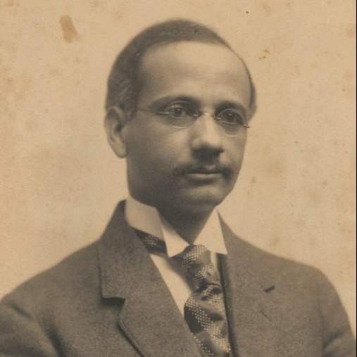 Old black and white image of male in suit wearing glasses